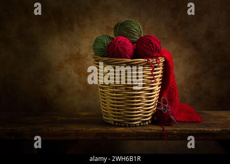 Korb mit grünen und roten Wollkugeln auf einem rustikalen alten Holzregal. Dies ist für das digitale Compositing geeignet. Stockfoto