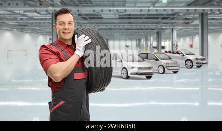 Mechaniker, der einen Autoreifen in einer Garage trägt Stockfoto