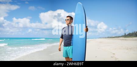 Ein Mann mit einem Surfbrett, der an einem Strand in Kuba, Varadero, steht Stockfoto