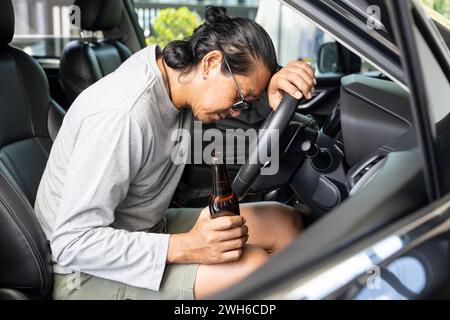 Asiatische Männer tranken Bier, während sie in der Dämmerung auf der Straße unterwegs waren, gefährliches Fahrkonzept Stockfoto