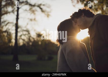 Porträt eines glücklichen Liebespaares im Park bei Sonnenuntergang. Ein Paar in der Silhouette küsst. Stockfoto
