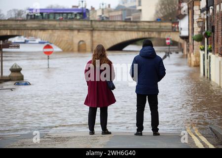 Die Menschen in York stehen und starren auf das Wasser neben den überfluteten Ufern des Flusses Ouse, während Sturm Jocelyn trifft und starke Winde und Regen weitere f Stockfoto