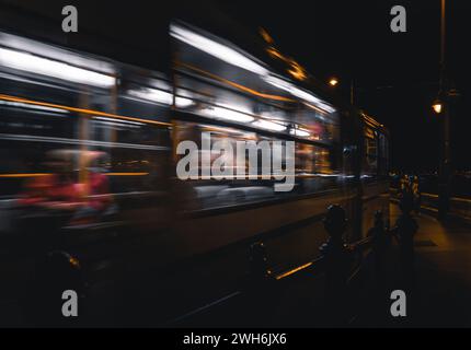 Person, die auf dem Bahnsteig steht, während der Zug nachts vorbeifährt Stockfoto