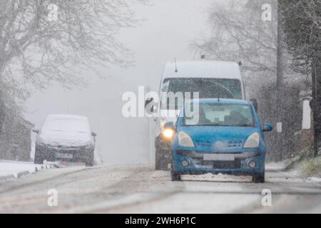 Flintshire, Nordwales, Vereinigtes Königreich. Wetter in Großbritannien. Am 8. Februar 2024, mit einer starken gelben Warnung vom Met Office für Flintshire, fällt in der Gegend starker Schnee. Verkehr entlang der Hauptstraße im Dorf Lixwm, Flintshire ©DGDImages/Alamy Live News Stockfoto