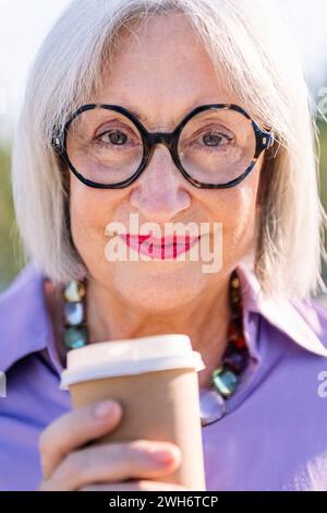 Lächelnde Seniorin mit einem Kaffee zum Mitnehmen Stockfoto