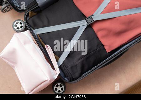 Öffne einen pinkfarbenen Koffer mit Kleidung für Reisen. Reisekonzept Stockfoto