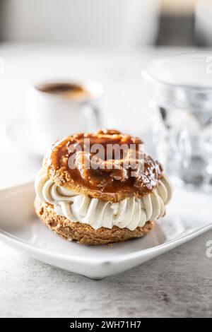 Veternik: Süßer Donut, typisch slowakischer süßer Kuchen mit Sahnefüllung, garniert mit Karamell auf einem Teller in einem Café. Stockfoto