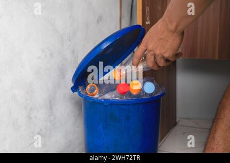 Männliche Hand wirft leere Plastikflaschen in den Recyclingbehälter Stockfoto