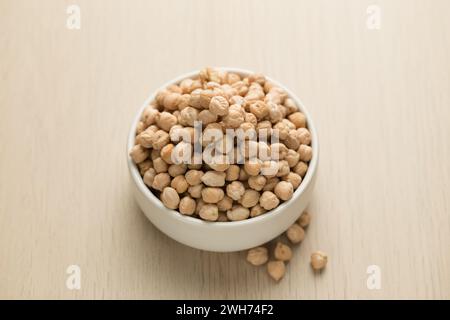 Kichererbsen in einer kleinen weißen Schüssel auf einem Holztisch. Stockfoto