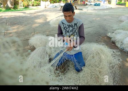 Lampung, Indonesien, 16. Oktober 2022: Gewerbliche Fischer reparieren oder sticken beschädigte Netze in einem Trockengebiet. Lebensstil-Konzept der indigenen ethnischen G Stockfoto