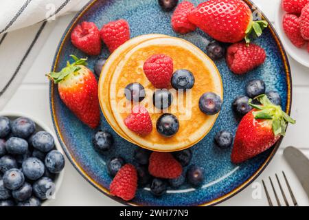 Die hausgemachten klassischen amerikanischen Pfannkuchen mit Heidelbeeren, Himbeeren und Erdbeeren. Draufsicht. Stockfoto