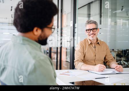 Das vielfältige Team während des Meetings. Zwei Profis nehmen an einem produktiven Brainstorming-Seminar in einer modernen Büroumgebung Teil, wobei eine Person einen Punkt erklärt und der andere aufmerksam zuhört Stockfoto