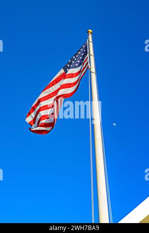 Die majestätische amerikanische Flagge winkt an einem sonnigen Tag vor einem klaren blauen Himmel Stockfoto