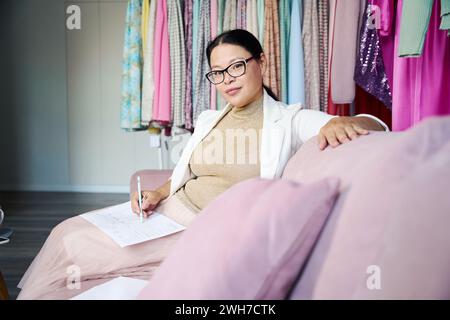 Frau in Brille arbeitet mit Papieren auf einem bequemen Sofa Stockfoto