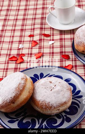 Das Bild zeigt zwei stimulierende Donuts auf einem Teller. Die Donuts sind mit einer Schicht Puderzucker bedeckt und haben eine runde, pralle Form. Stockfoto