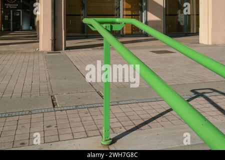 Handlauf am Eingang eines öffentlichen Gebäudes, um Personen beim Treppensteigen zu unterstützen. Elemente aus grünem Stahl, unverzichtbar und widerstandsfähig Stockfoto