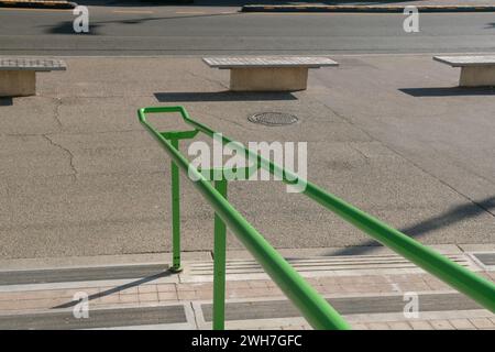 Handlauf am Eingang eines öffentlichen Gebäudes, um Personen beim Treppensteigen zu unterstützen. Elemente aus grünem Stahl, unverzichtbar und widerstandsfähig Stockfoto