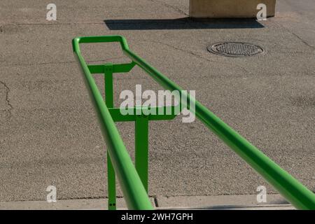 Handlauf am Eingang eines öffentlichen Gebäudes, um Personen beim Treppensteigen zu unterstützen. Elemente aus grünem Stahl, unverzichtbar und widerstandsfähig Stockfoto