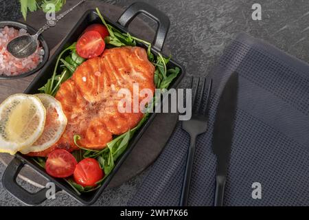 Gegrilltes Lachssteak mit Rucolasalat, Tomaten und Schalotten. Das Konzept der gesunden Ernährung, Ernährung, kalorienarm. Stockfoto
