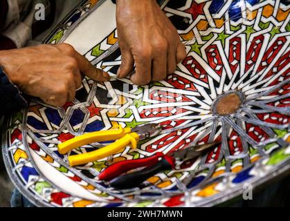 Marokkanischer Handwerker, der ein Mosaik auf eine traditionelle handgefertigte Schüssel zum Verkauf auf dem Markt einlegt Stockfoto