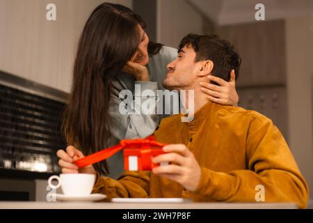Liebes- und Weihnachtsfeier, lächelnde Frau überrascht ihren Freund mit einem Geschenk zu Hause Stockfoto