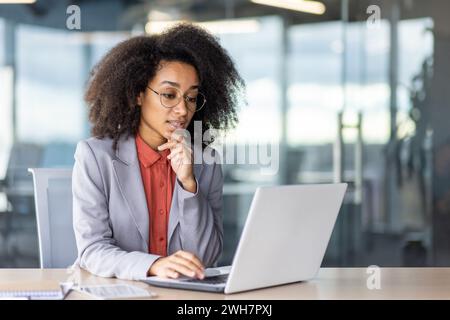 Eine Frau arbeitet an einem Laptop an einem Schreibtisch und nutzt einen PC als Ausgabegerät. Stockfoto