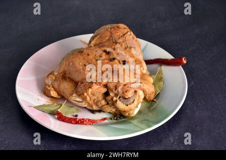 Ein Schenkel putenfleisch, gedünstet mit Gemüse und Gewürzen, liegt auf einem Teller. Stockfoto