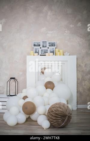 Ein gefälschter Kamin ist mit weißen und braunen Ballons dekoriert Stockfoto