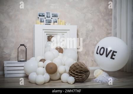 Ein gefälschter Kamin ist mit weißen und braunen Ballons dekoriert Stockfoto
