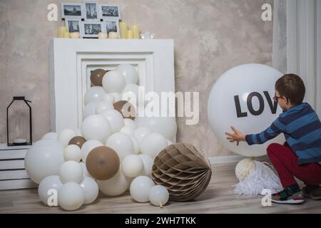 Ein Junge dekoriert einen falschen Kamin mit weißen und braunen Ballons Stockfoto