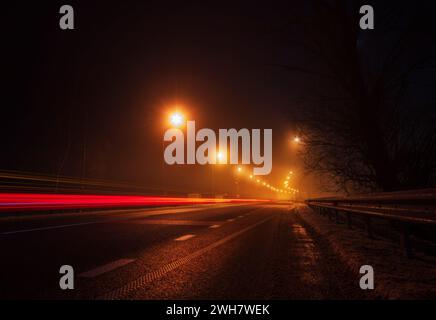 Leere Autobahn mit leichten Spuren vom vorbeifahrenden Auto bei Nacht. Stockfoto