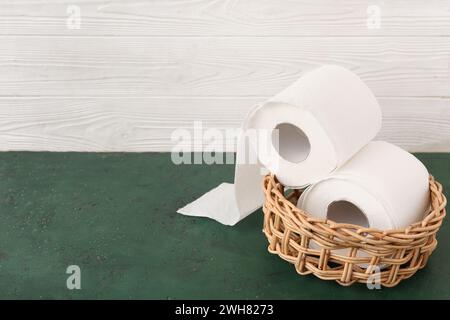 Korbschale mit Toilettenpapierrollen auf grünem Tisch Stockfoto