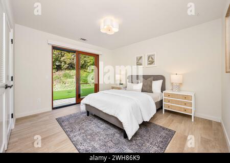 Bett und Schreibtisch in einem Schlafzimmer mit viel Tageslicht und elegantem Hartholzfußboden Stockfoto