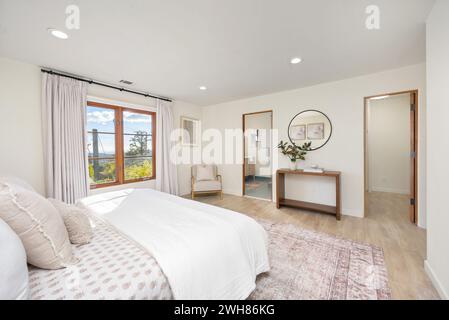 Geräumiges Schlafzimmer mit einem Kingsize-Bett und großen Fenstern mit atemberaubendem Blick auf den Außenbereich Stockfoto