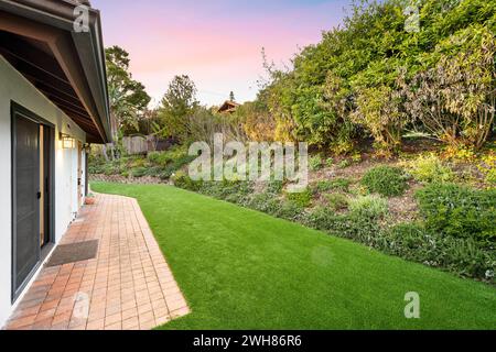 Backsteinpflaster Terrasse umgeben von üppigem Laub im Hinterhof eines Wohnhauses Stockfoto