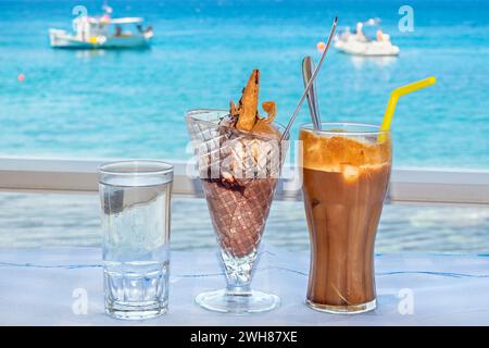 Gläser Wasser, Eis und Frappe auf einem Tisch im Strandcafé. Rhodos, Griechenland Stockfoto