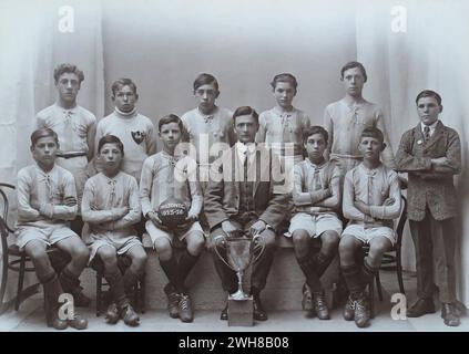 Portsmouth, Hampshire. 1926: Ein Foto der Milton F.C. Schulfußballmannschaft aus Milton, Portsmouth, aufgenommen nach dem Gewinn des Turniers „Evening News“ Schools Football Cup. Das Foto zeigt die Jungs in ihrem Fußballtrikot, die mit ihrem Lehrer/Trainer und dem Pokal posieren. An ihre Hemden geheftet sind die Preismedaillen, die ihnen verliehen wurden. Das Finale fand am 1. April 1926 zwischen der Milton School und der Reginald Road School im Portsmouth F.C.’s Ground, Fratton Park, statt. Milton gewann das Spiel mit zwei Toren gegen Null. Stockfoto