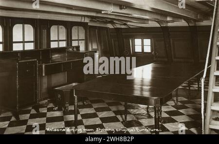 Portsmouth. Ca. 1930er Jahre Eine alte, echte Fotopostkarte mit dem Titel „Nelson’s Dining Room, Show original Furniture“, die den Speisesaal des Kapitäns auf der HMS Victory, einem erstklassigen Schiff der Royal Navy mit 104 Kanonen, darstellt. Das Schiff ist bekannt für seine Rolle als Horatio, Lord Nelsons Flaggschiff in der Schlacht von Trafalgar am 21. Oktober 1805. Sie befindet sich im Trockendock von Portsmouth Historic Dockyard in Hampshire und ist das älteste Marineschiff der Welt, das noch in betrieb ist. Stockfoto