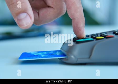 PIN-Code am Zahlungsterminal mit dem Finger wählen. Transaktionszahlung und Einkaufskonzept. Nahaufnahme Stockfoto