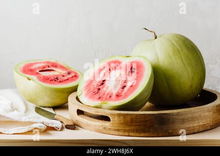 Reife rosafarbene Wassermelone in zwei Hälften auf einem Holztablett. Stockfoto