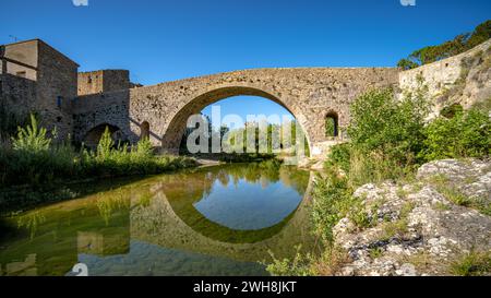 Die alte mittelalterliche Steinbrücke von Lagrasse, Frankreich, an einem sonnigen Frühlingsmorgen ohne Menschen aufgenommen. Stockfoto