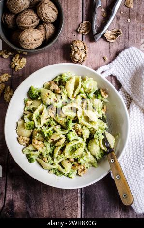 Pasta mit Brokkoli und Walnusspesto in einer Schüssel auf Holztisch Stockfoto