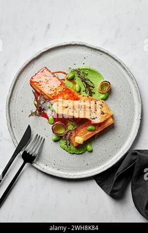 Gegrilltes Lachsfilet, Miso-Kartoffelgratin, Edamam- und Lauch-Creme, Sesamtuile Stockfoto