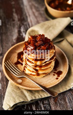 Apfelzimtpfannkuchenstapel auf hölzerner Oberfläche und Salbei grünem Hintergrund Stockfoto