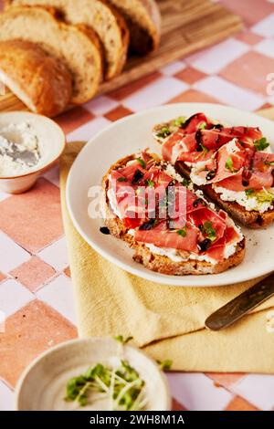 Ricotta- und Parmaschinken-Toast mit Balsamico-Drizzle und Kresse auf gekacheltem Hintergrund Stockfoto