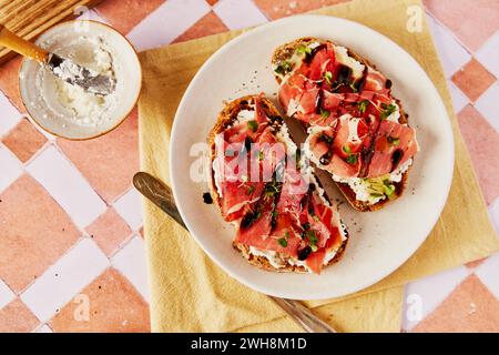 Ricotta- und Parmaschinken-Toast mit Balsamico-Drizzle und Kresse auf gekacheltem Hintergrund Stockfoto