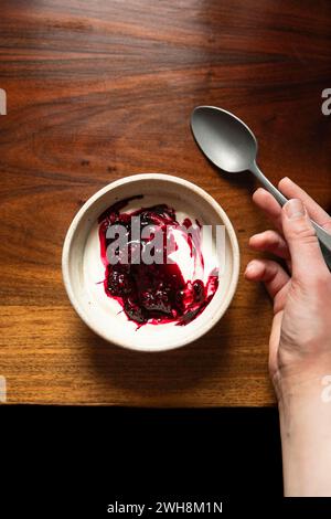 Schüssel mit Joghurt und brombeerkompott auf einem Holztisch mit silbernem Löffel. Stockfoto