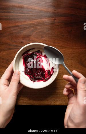 Schüssel mit Joghurt und brombeerkompott auf einem Holztisch mit silbernem Löffel. Stockfoto