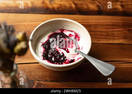 Schüssel mit Joghurt und brombeerkompott auf Holztisch mit Silberlöffel. Stockfoto