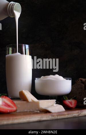 Gesunde probiotische Molkerei, einschließlich Kefir, griechischer Joghurt und Parmgiano reggiano. Kefir aus der Flasche gießen. Stockfoto